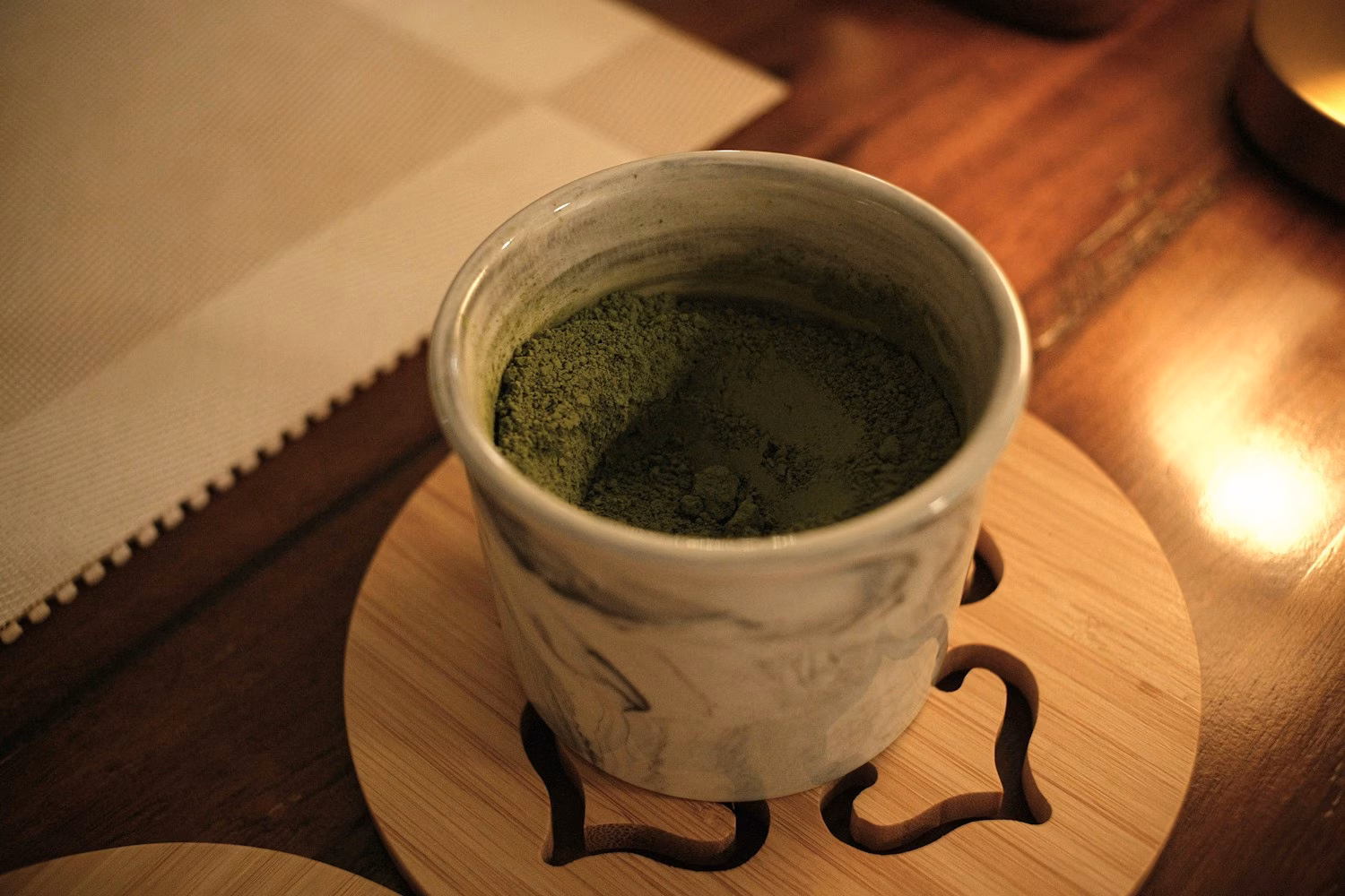 Polvere di matcha in una tazza di ceramica su un sottobicchiere in legno
